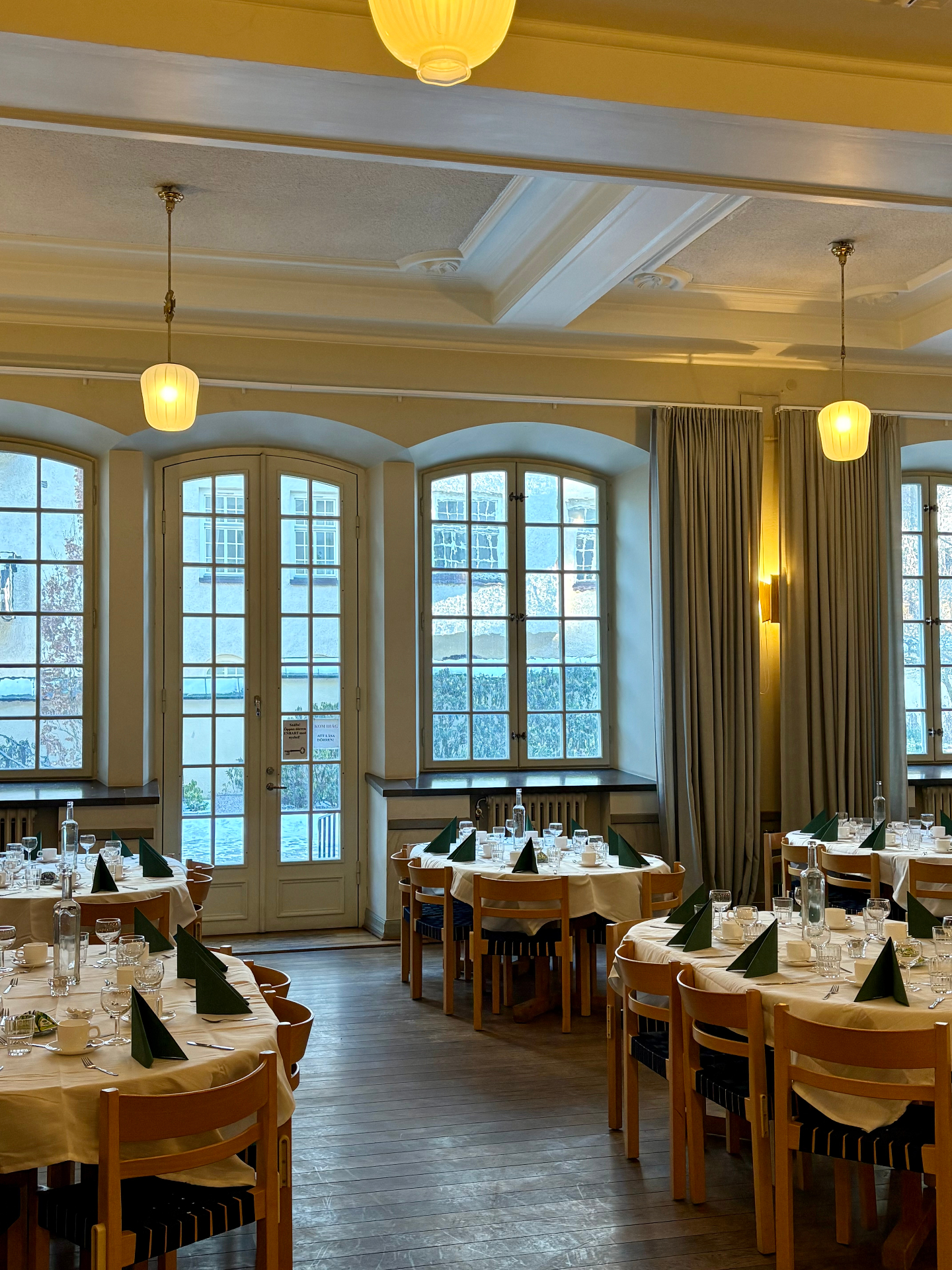 Sal med dukade bord och gröna servetter